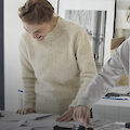 An artist looks at negatives on a table with the team from an archive.