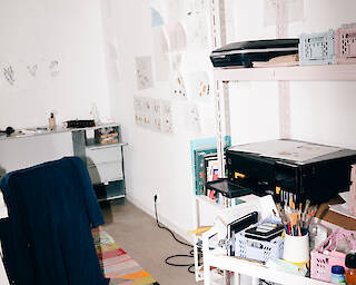 View into a studio. You can see a shelf with various tools and lots of pictures hanging on the wall.