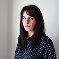 Portrait of Elena Efeoglou. She has long dark hair and is wearing a blouse with white dots.